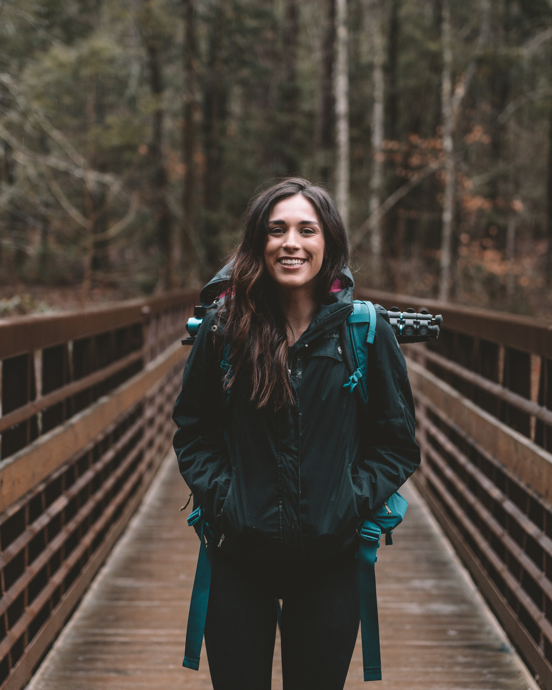Brunette woman smiling at camera on hiking trail