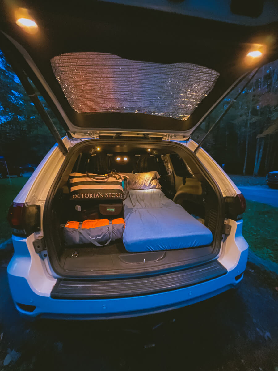 Car camping setup inside a Jeep Grand Cherokee
