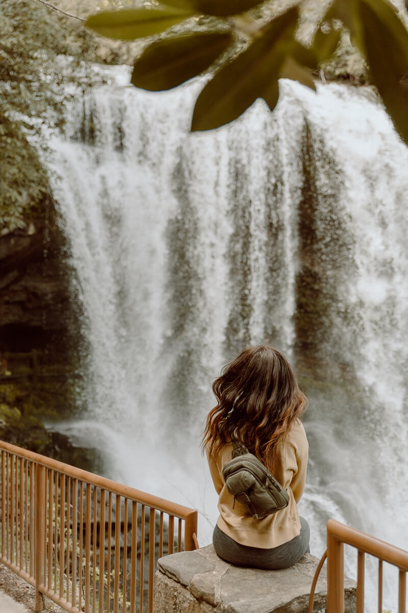 Woman sitting in front of Dry Falls in Highlands, NC