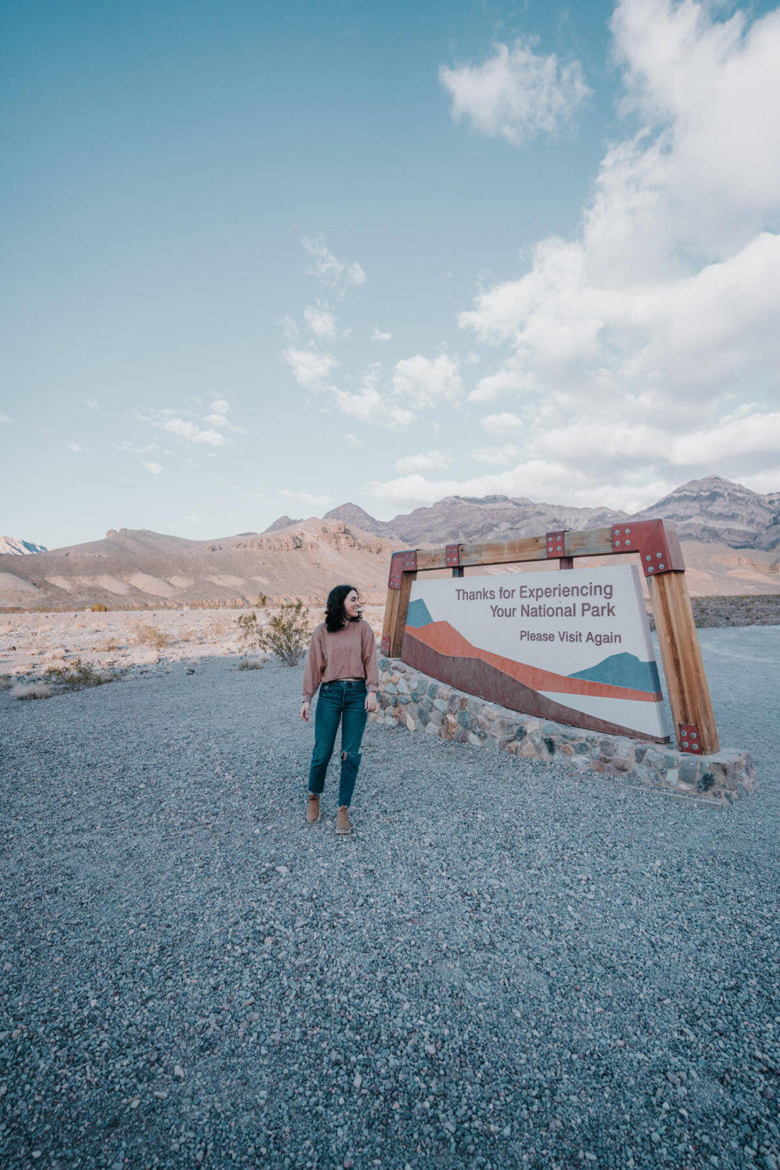 Woman smiling and standing beside Death Valley welcome sign