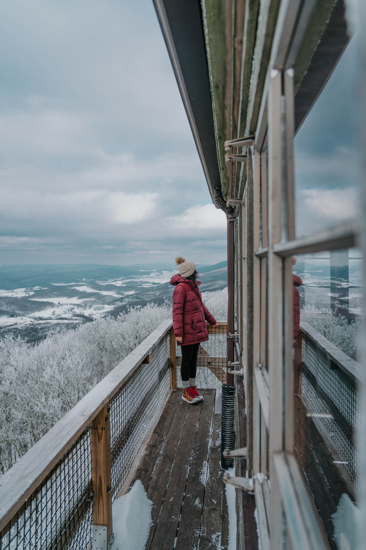 Woman standing on deck of lookout tower looking at mountains in the distance 
