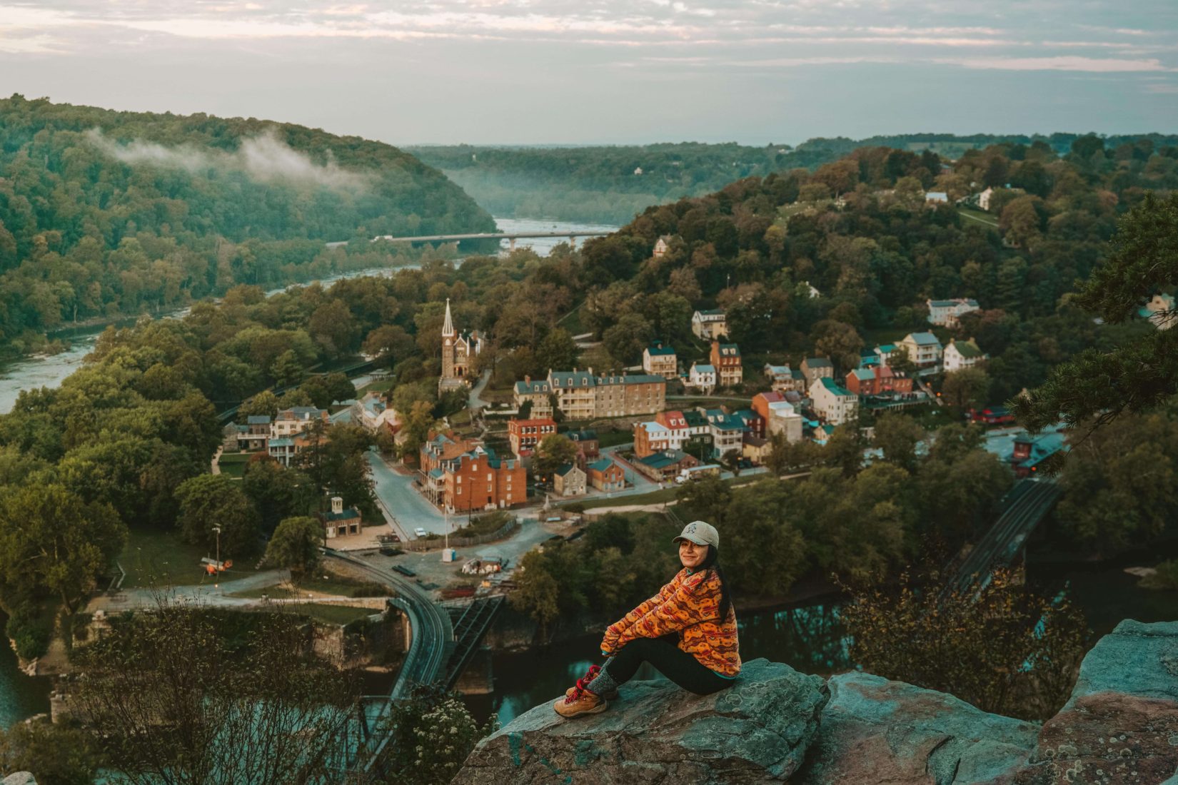 Woman sitting at overlook with downtown Harpers Ferry in the background