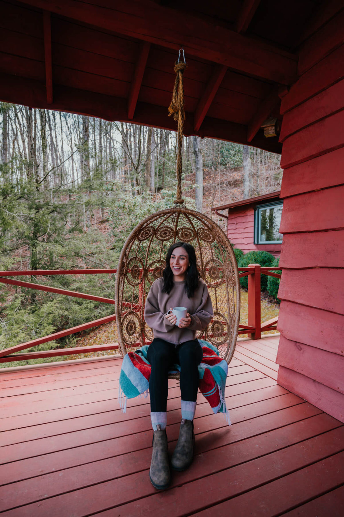 Woman sitting in porch swing, smiling and holding a coffee mug