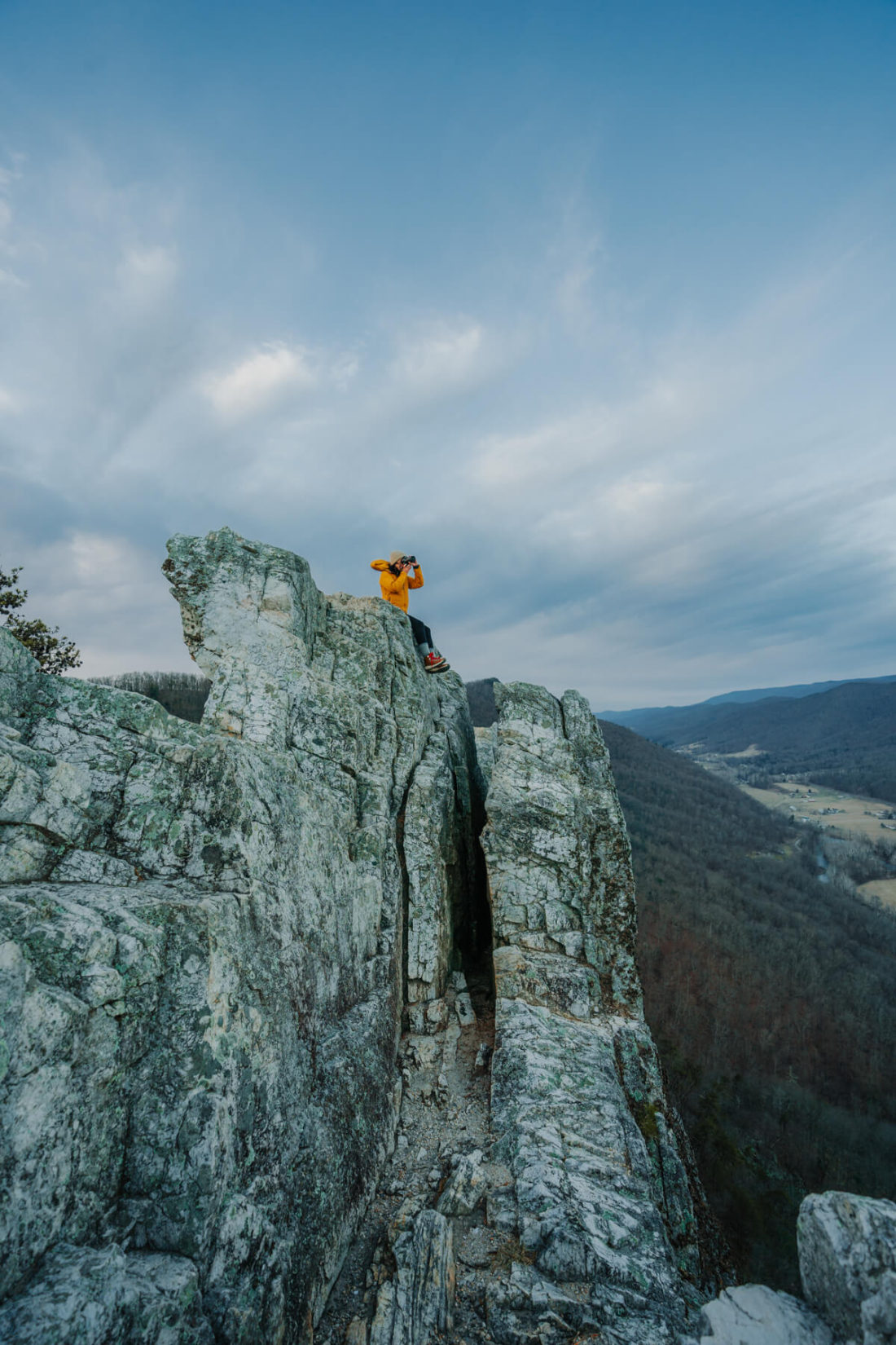 Hiker in yellow jacket sitting on rock formation at Seneca Rocks