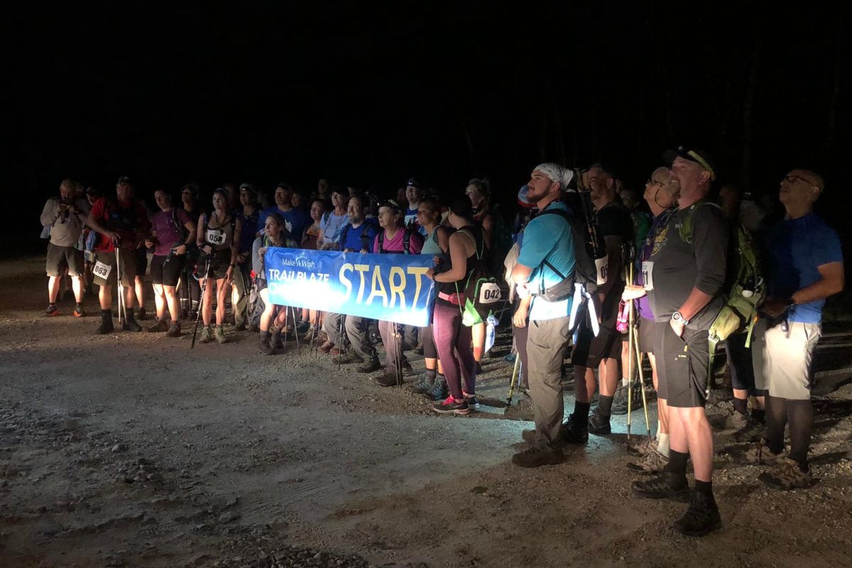 Group of hikers holding up a "Start" sign in the dark